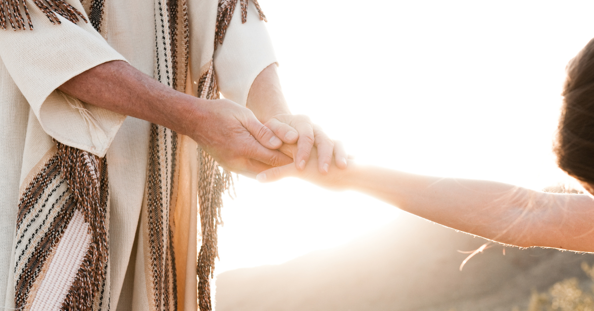 A figure in a robe, symbolizing Jesus, gently holds a person's hand in a gesture of guidance and compassion, reflecting themes of faith and connection in the story of Joseph, drawing parallels to finding Jesus in Joseph's journey.