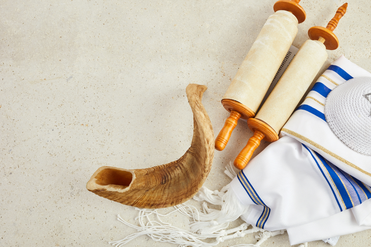 Jewish religious symbols including a shofar, Torah scrolls, and a tallit, representing themes of Jewish faith, tradition, and scripture.