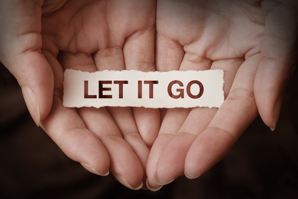 An image of open palms, holding a piece of paper with the words Let It Go.