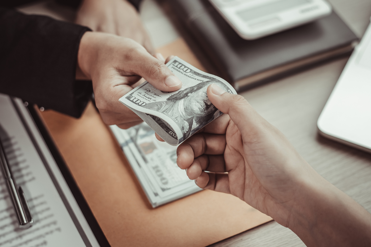 An image of a person handing out money to another person.