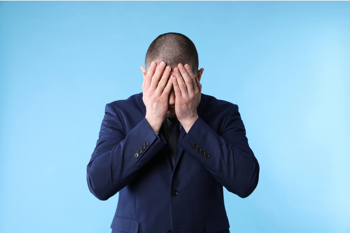 A man in a business suit with his face in his palms.