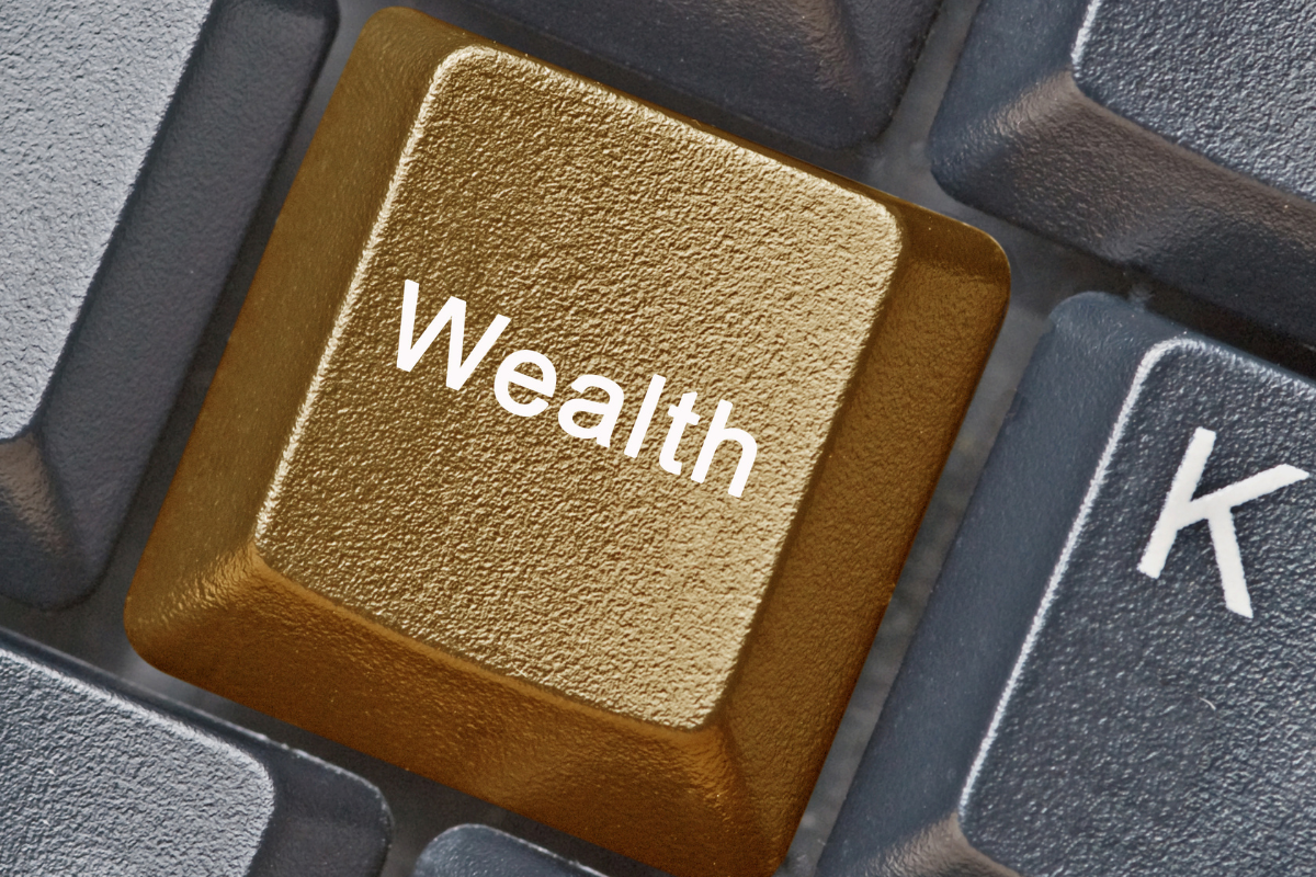 A golden key in a keyboard with the word Wealth on it.